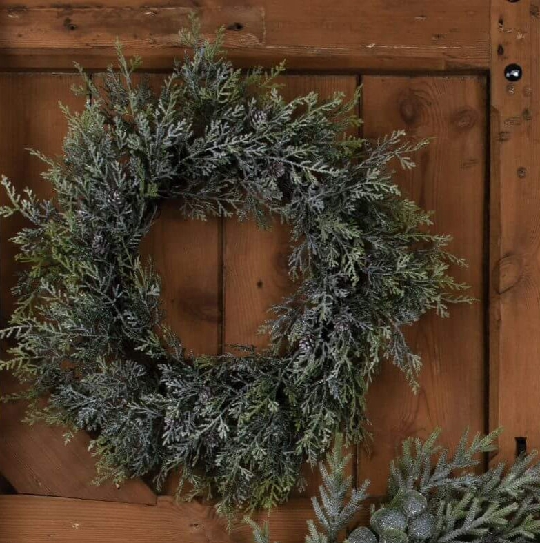 a bold close-up of a winter frosted pine and eucalyptus wreath with dramatic lighting