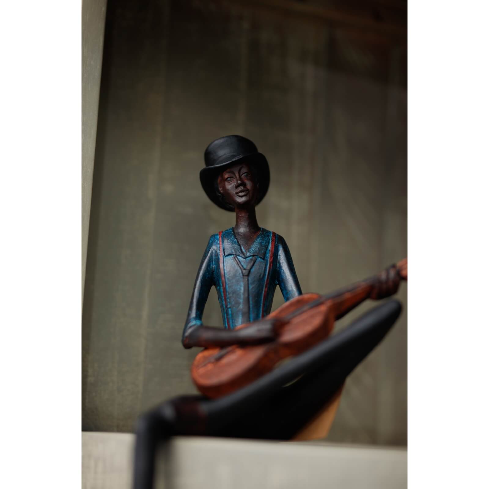 Handcrafted brown resin jazz guitarist sculpture with hanging leg, part of Sitting Jazz Band series. by sostter at brixbailey.com