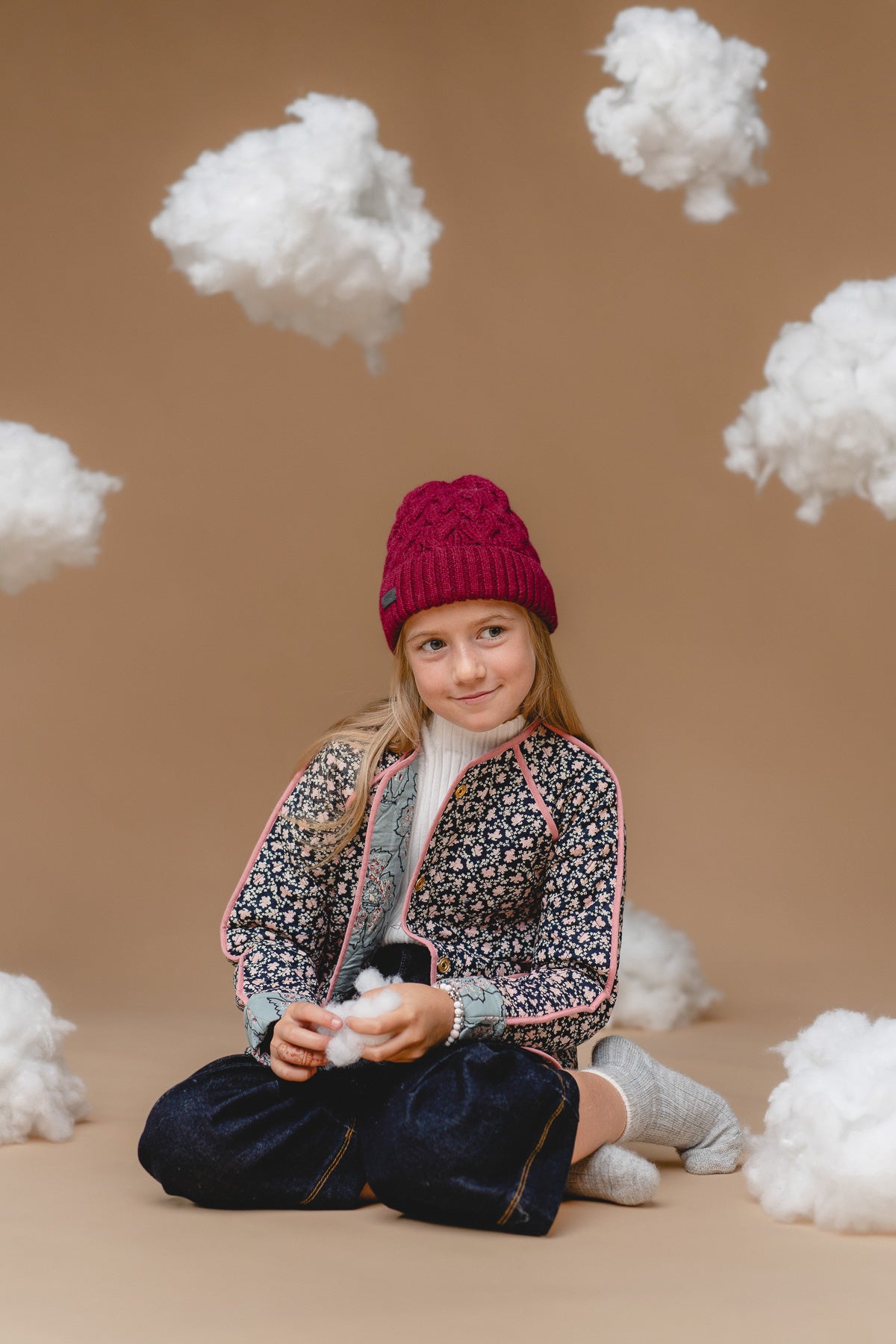 soft mulberry kids alpaca cable hat with a fluffy pompom, shown in gentle natural light
