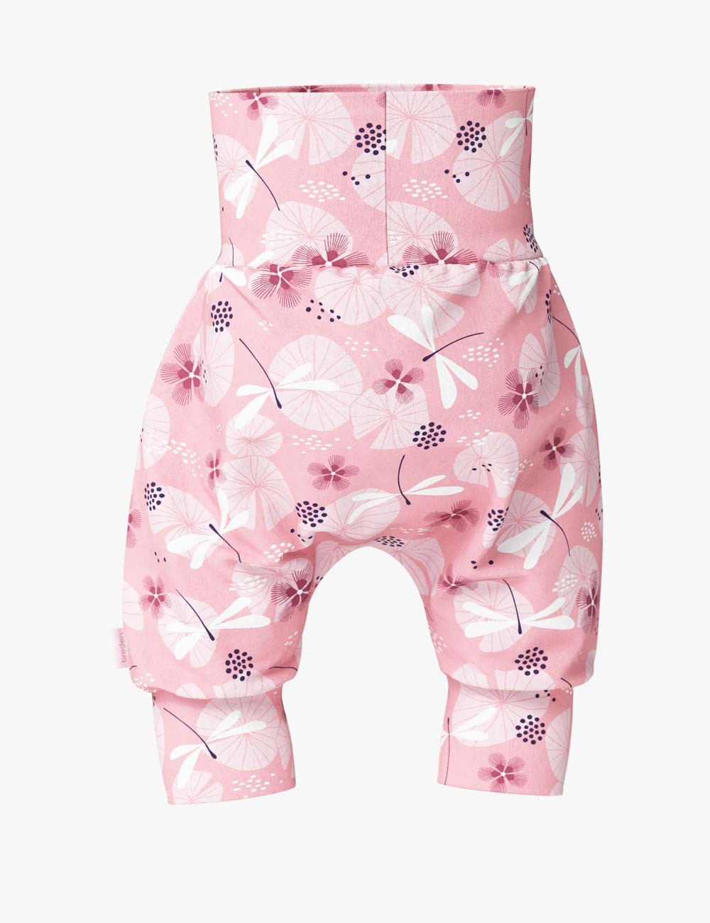 playful baby in dragonfly shorts crawling on a sunny lawn