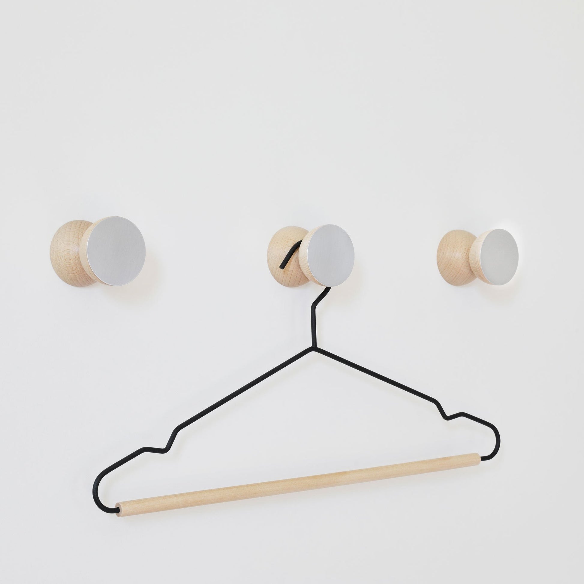 bold geometric wall hook in brushed aluminium and warm beech wood, a confident modern statement