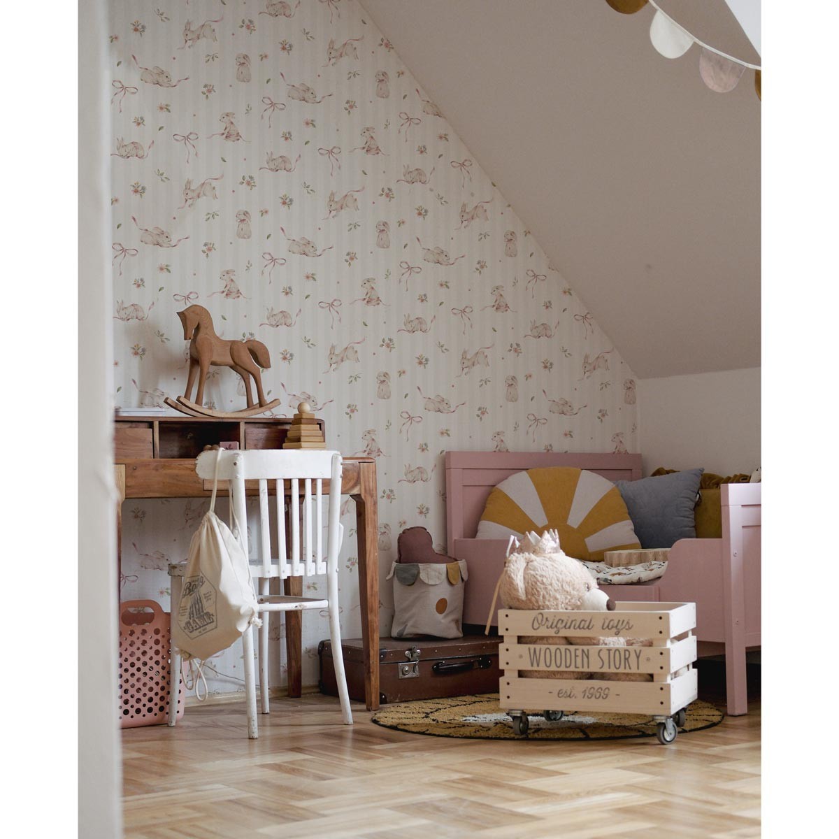 playful pink bunnies peeking from behind soft stripes on kids wallpaper