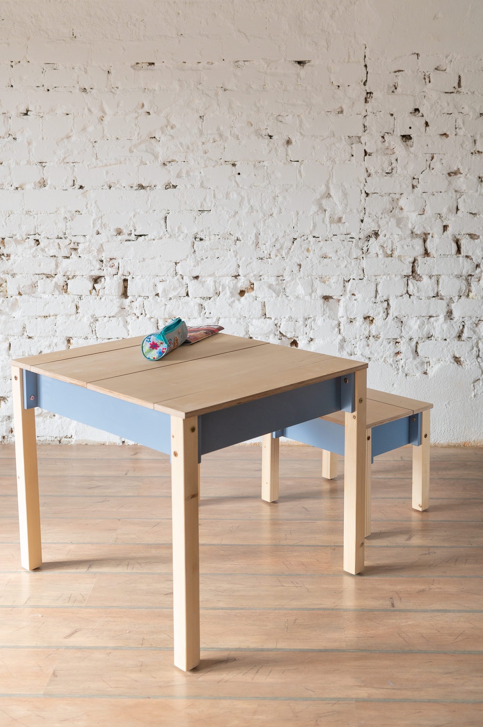 a child's compact birch wood table and chair set with storage, shown in a warm morning light