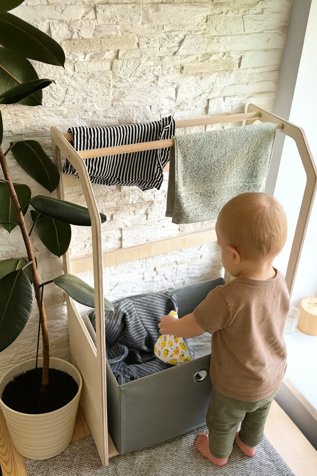 a child's wooden drying rack with a green fabric basket in a bright, sunlit playroom