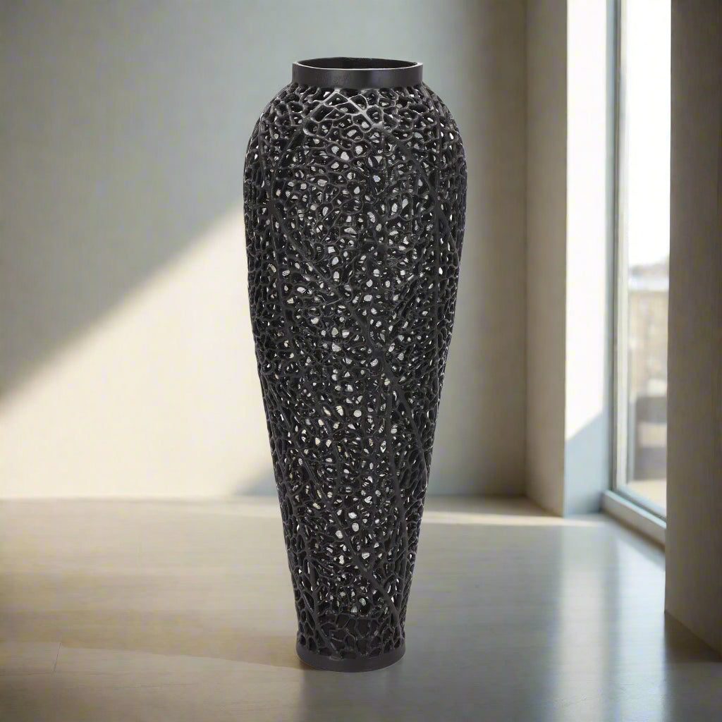 Matte black perforated steel vase with geometric cutouts, creating dynamic light patterns, 90cm tall, modern home decor by Sostter at brixbailey.com