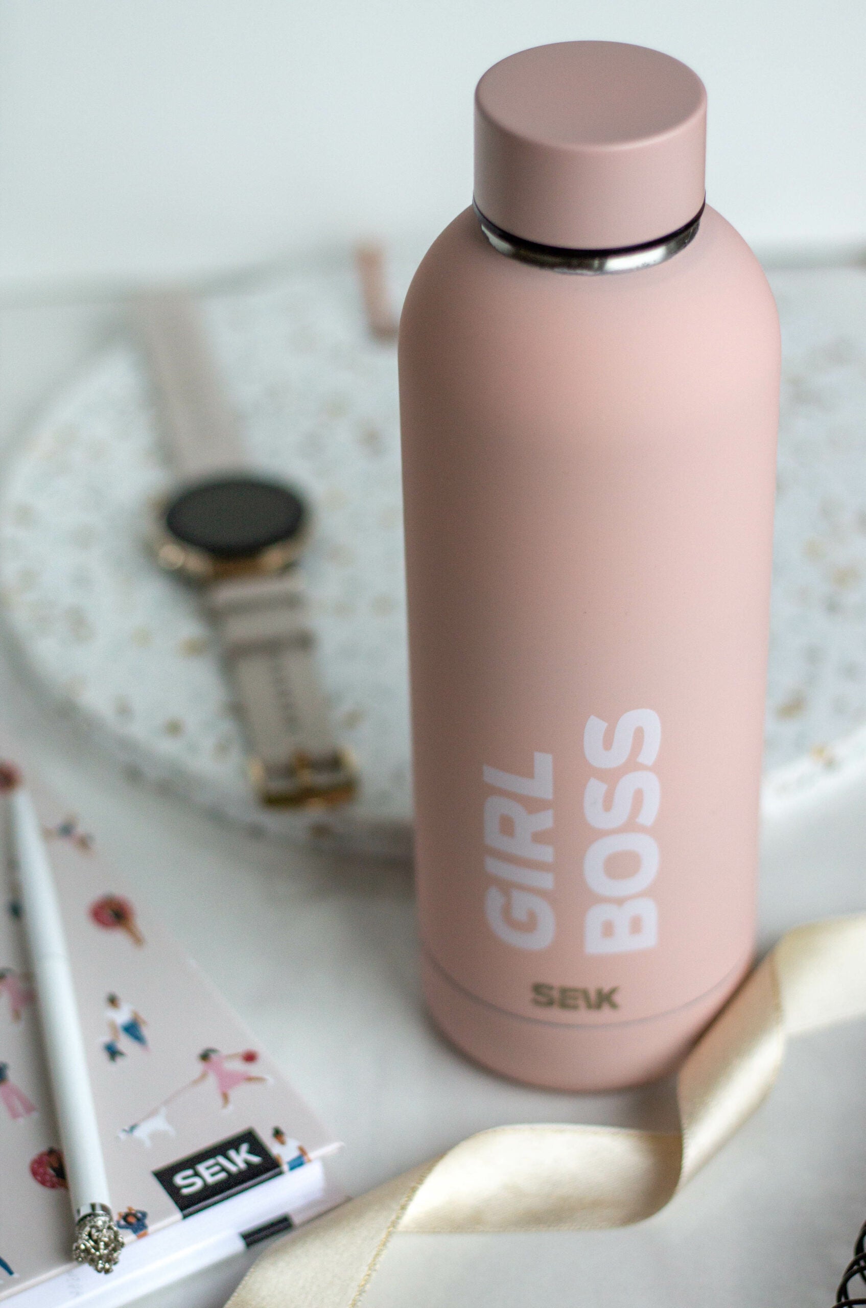 a soft-lit view of the seik girl boss thermos resting on a cozy surface, showcasing its comforting and elegant design