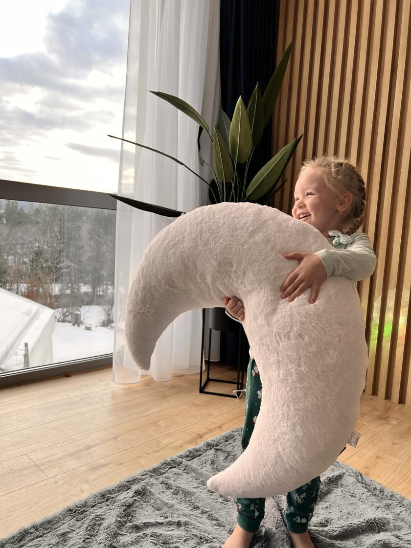 a soft grey crescent moon pillow for a nursery, shown in warm morning light
