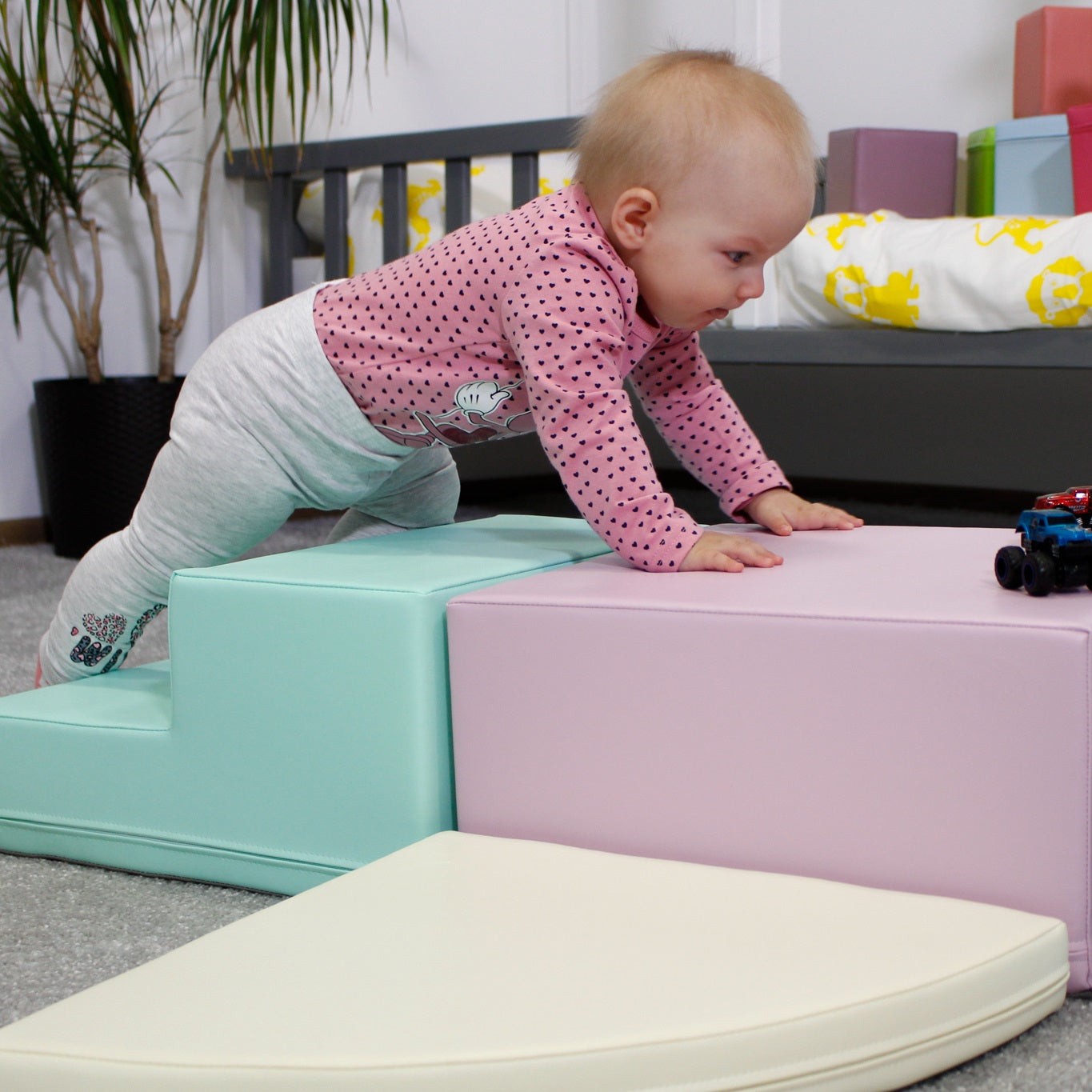 a toddler laughing while climbing a pastel foam block corner climber