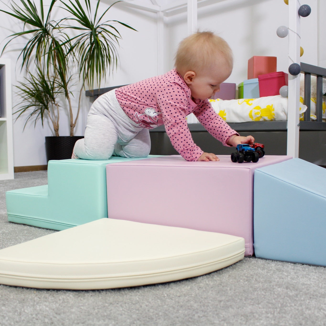 a child's hand reaching for a pastel foam climber block in a sunlit playroom