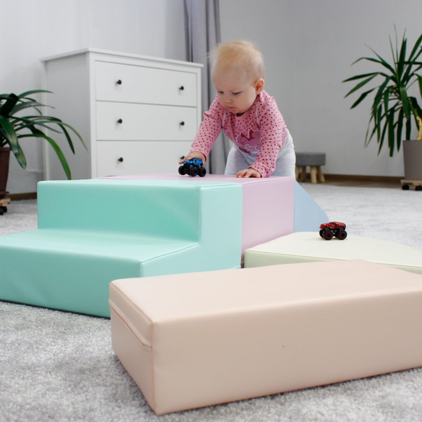 a toddler climbing on a soft pastel foam block corner climber in a sunlit playroom