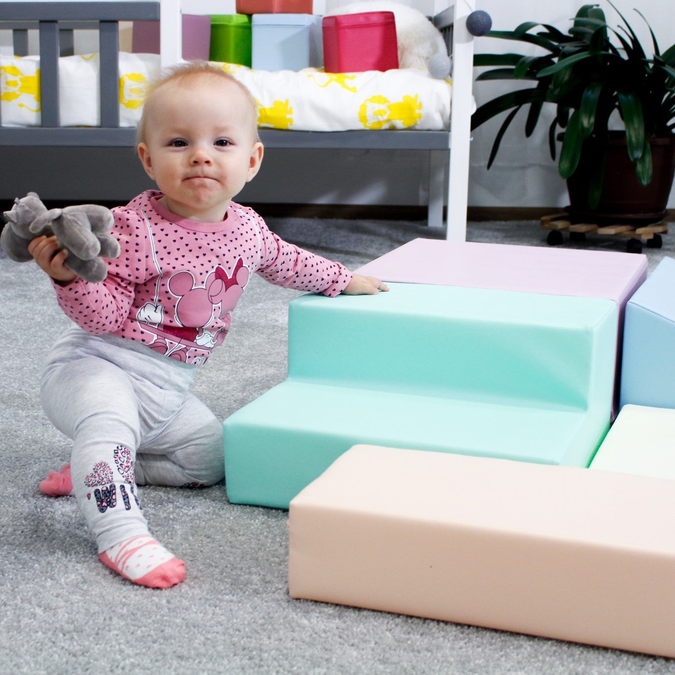 aerial view of a toddler climbing on a soft pastel foam block climber in a sunlit playroom