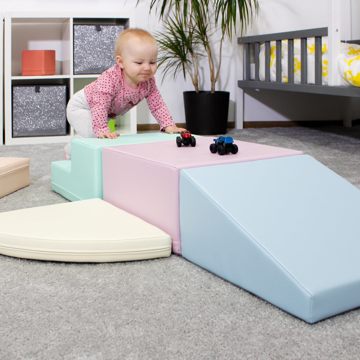 a toddler climbing on a soft pastel foam block climber from a low side angle