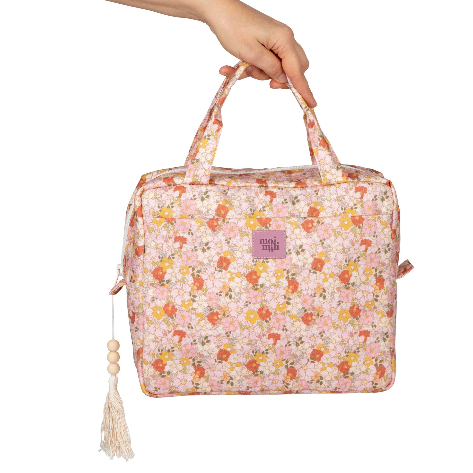 large spring garden makeup bag with floral print, open to show waterproof lining and pockets, resting on a wooden table