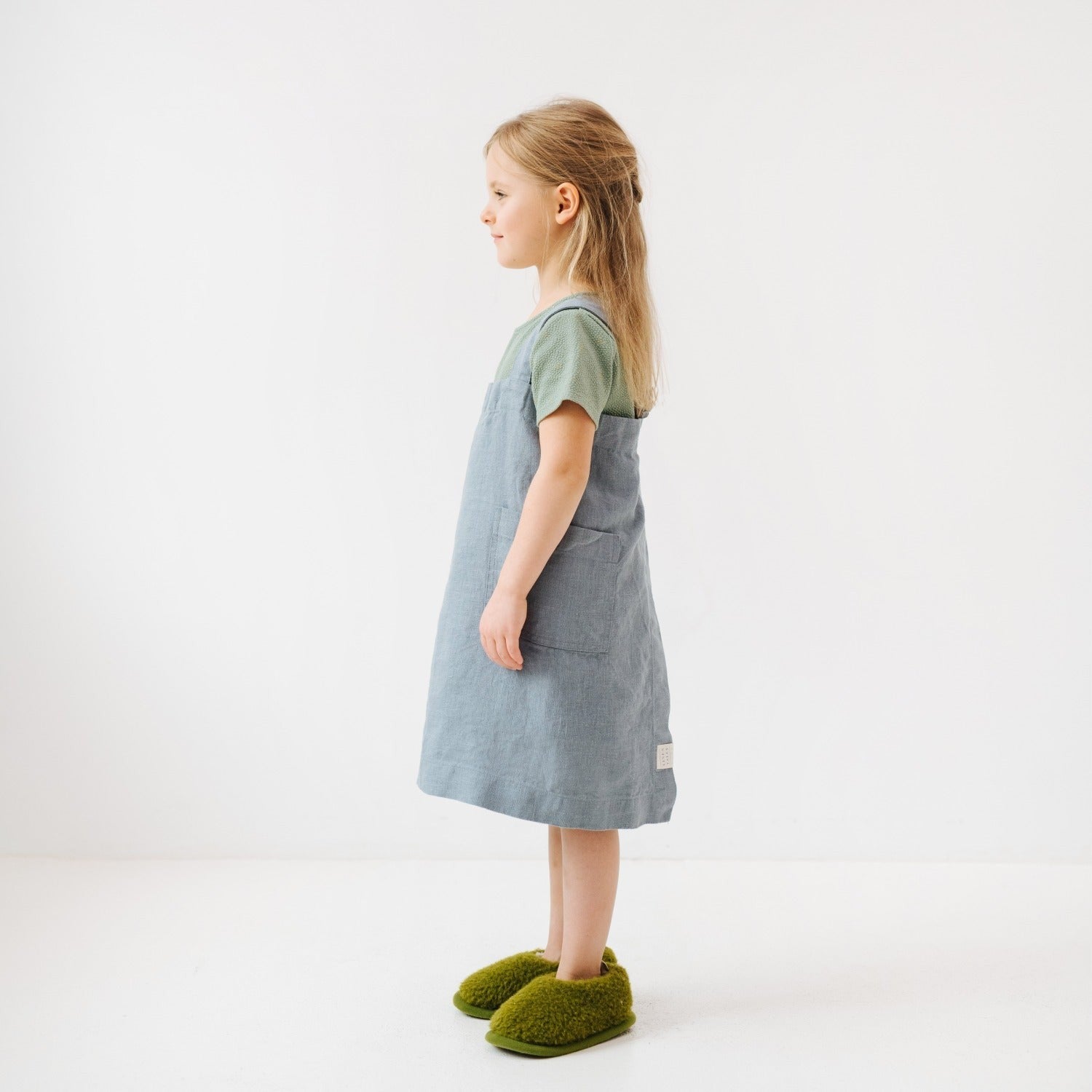 elegant blue fog linen kids apron on a rustic wooden table, highlighting its refined handmade texture