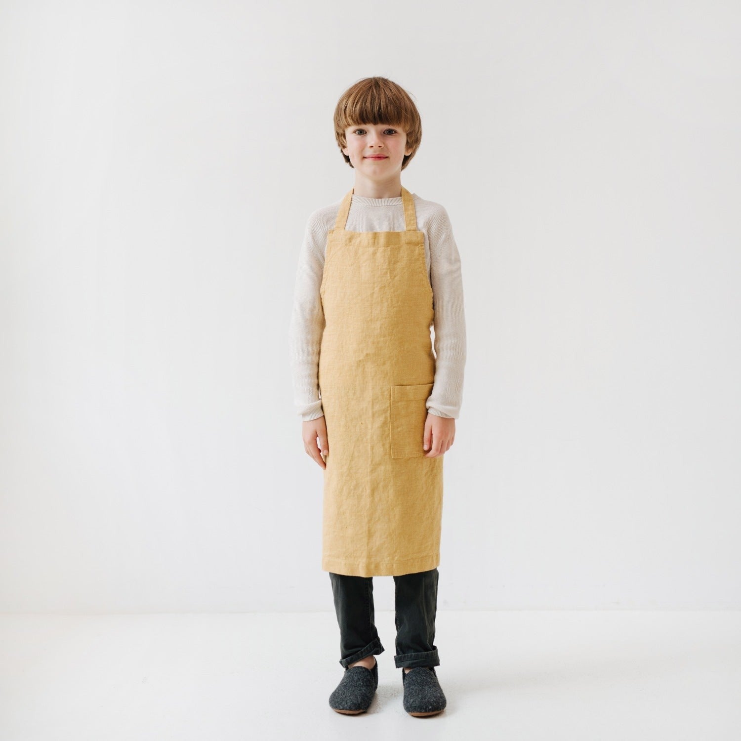 close-up of the honey kids linen apron's front pocket holding a wooden spoon