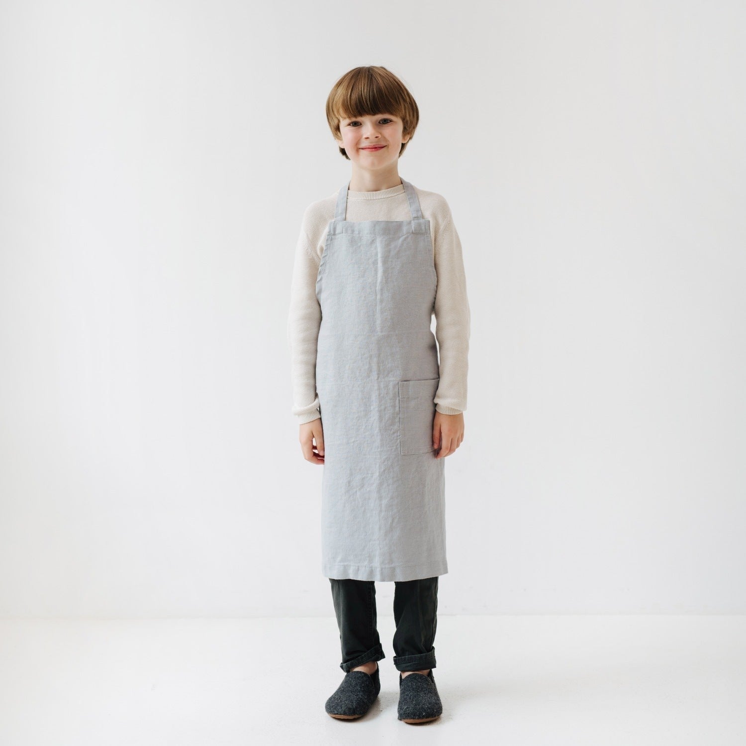 a child's functional linen apron with a front pocket for holding cooking tools
