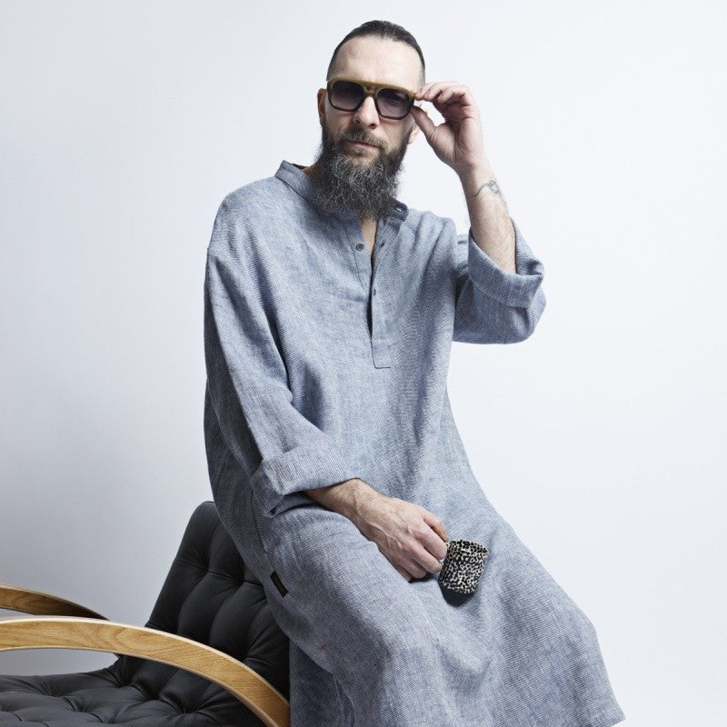 a man in a refined blue-gray linen dress standing in soft, elegant light