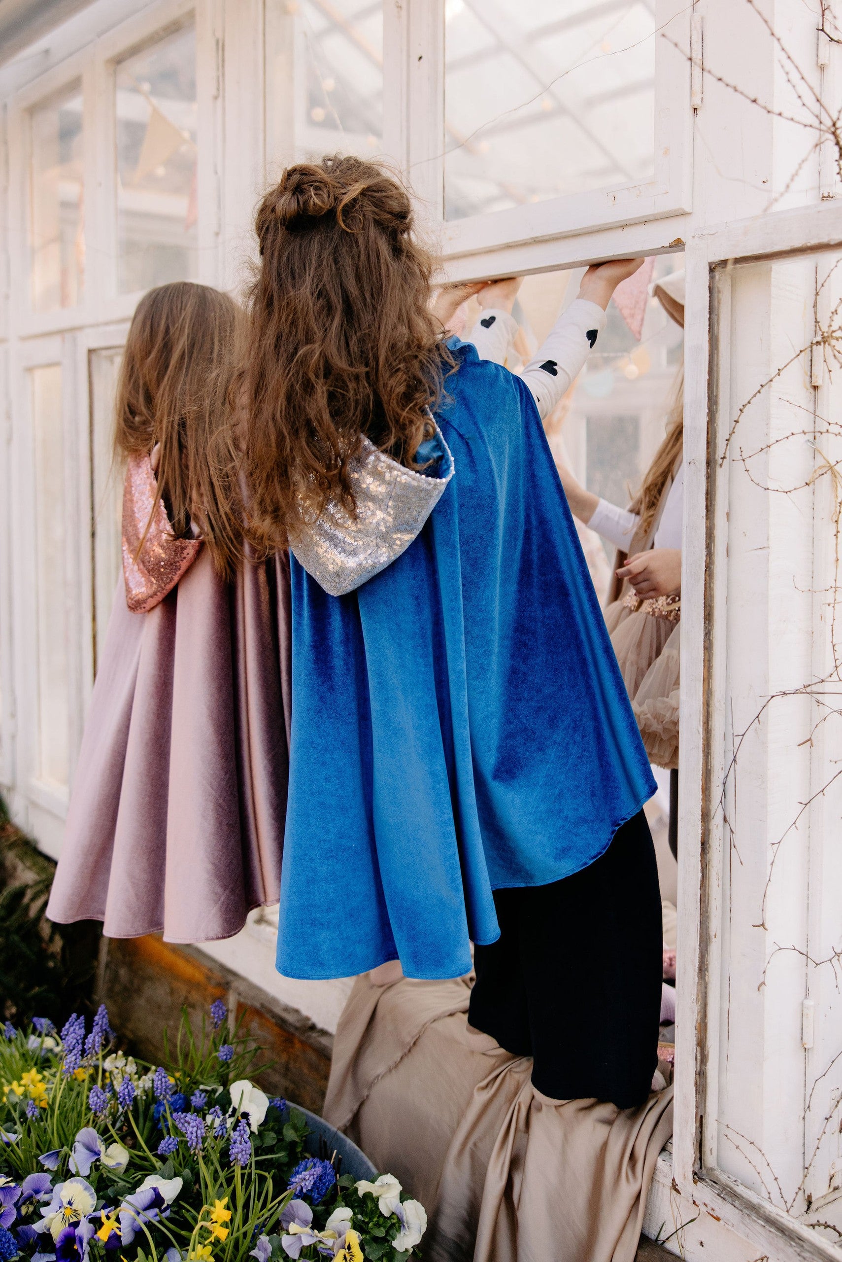 handmade snow queen cape with a deep blue hood and velour fabric, seen from a functional angle highlighting its secure snap closure and play-friendly hand holes