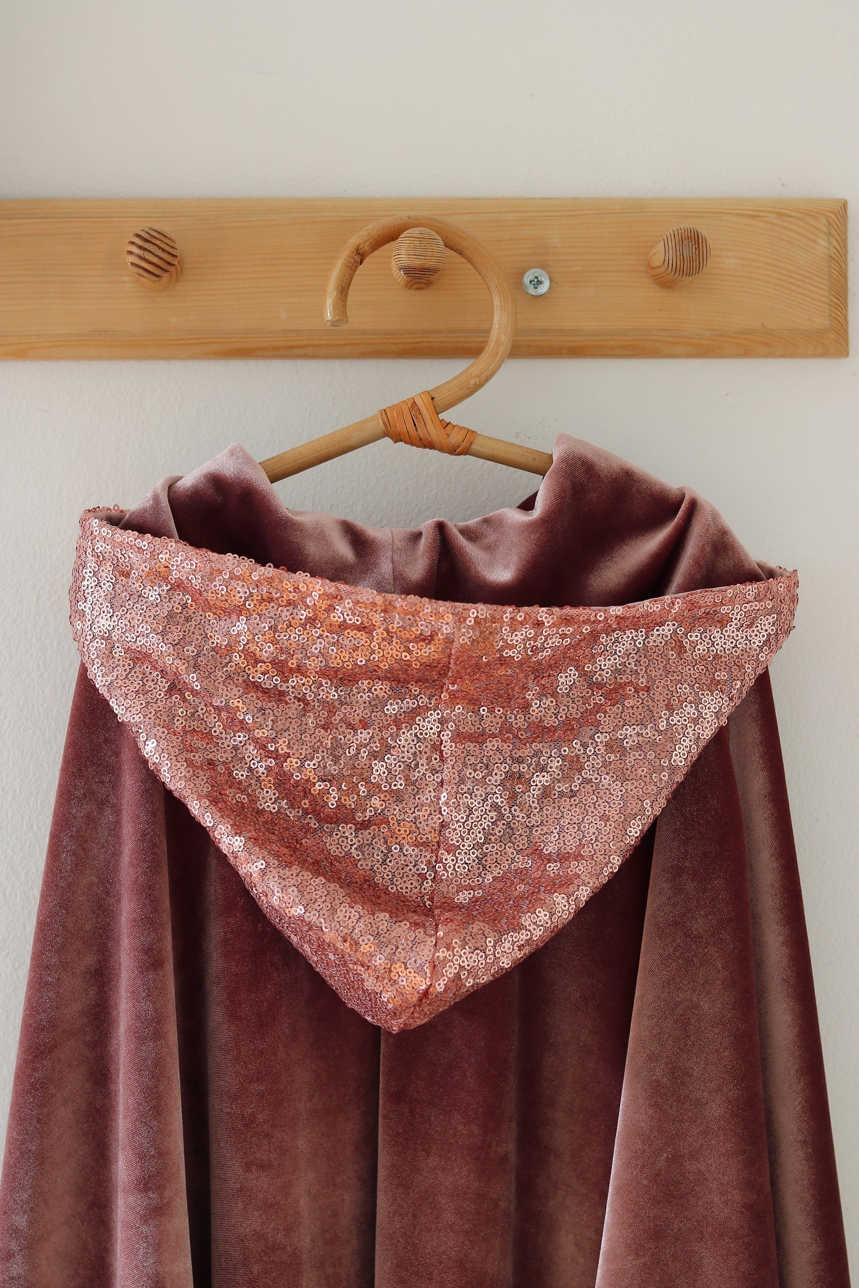 a soft pink velour hooded cape for kids, shown from a gentle side angle in cozy morning light
