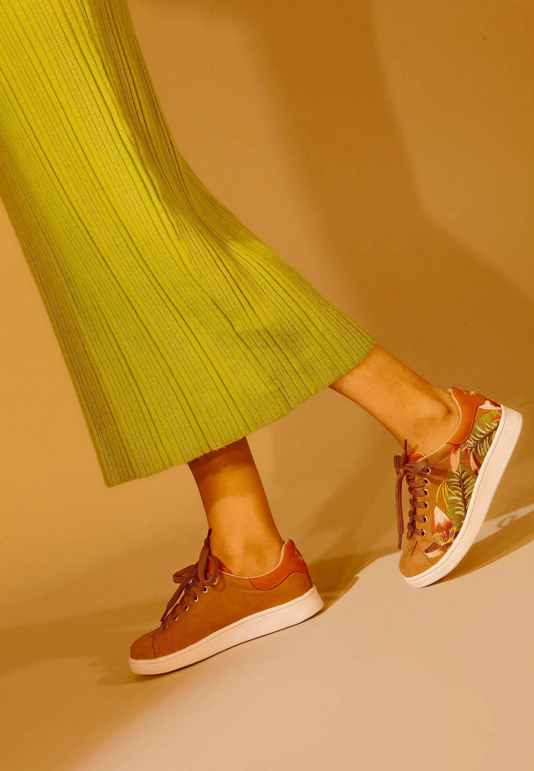 elegant brown suede sneaker with detailed floral embroidery on a soft-focus background