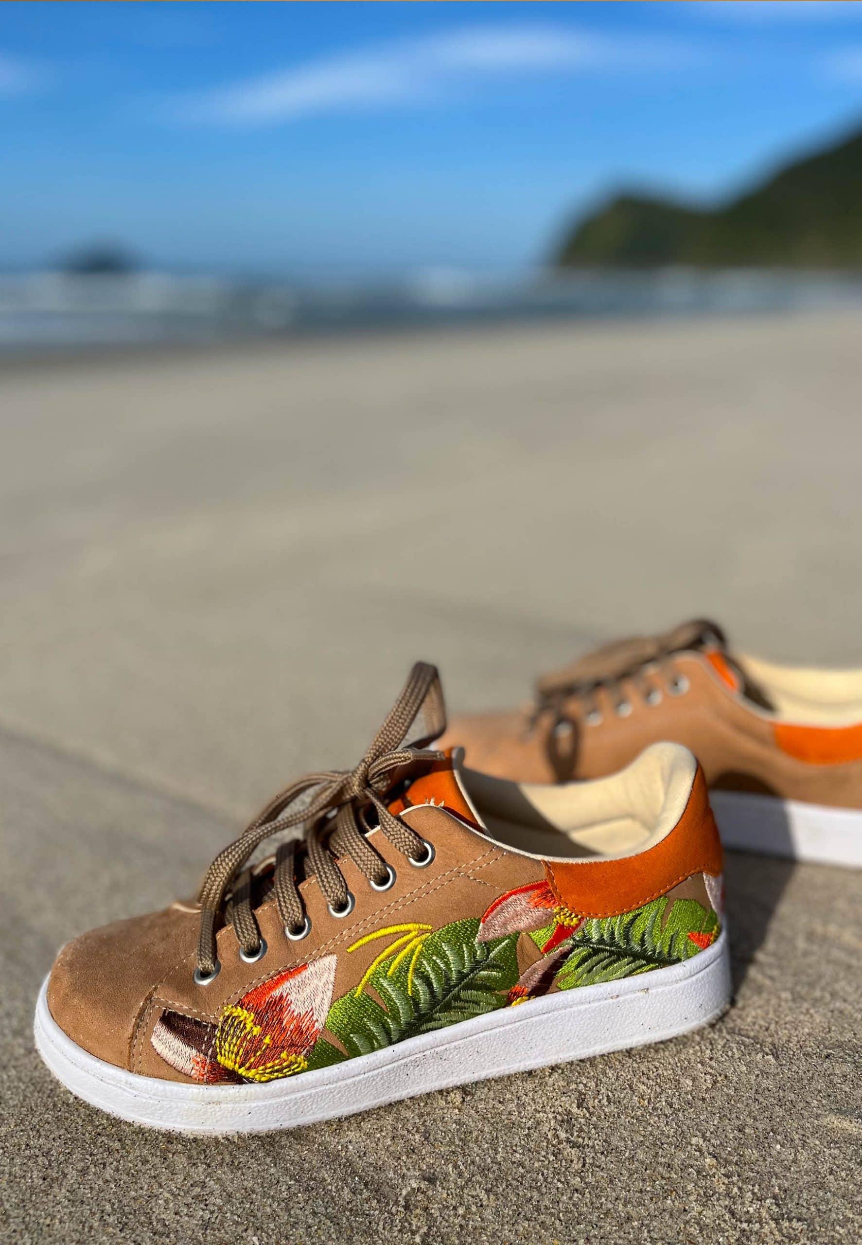 side profile of mangara floral embroidered suede sneakers on a rustic wooden deck
