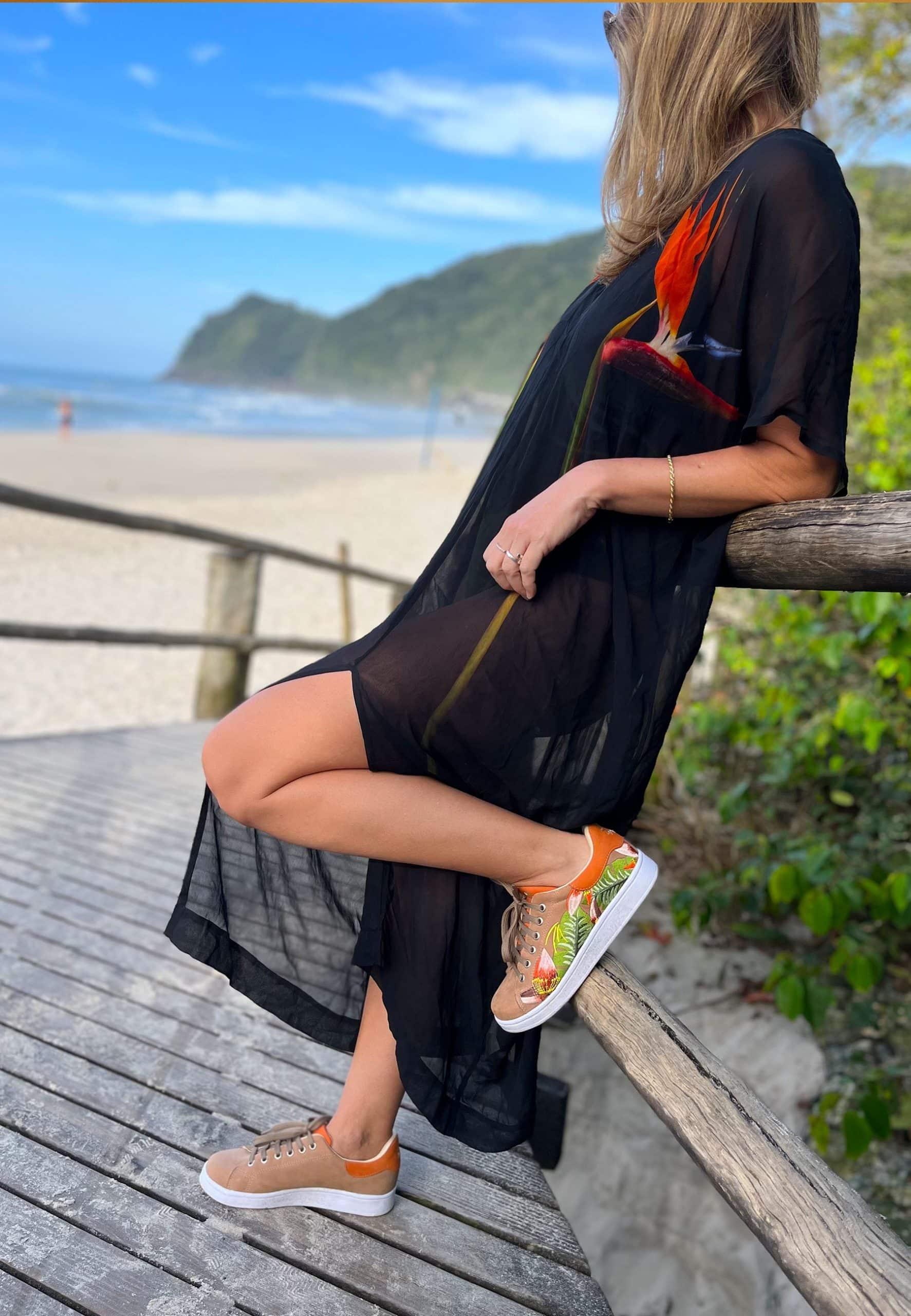 side view of soft brown suede sneakers with intricate floral embroidery on a warm wooden background