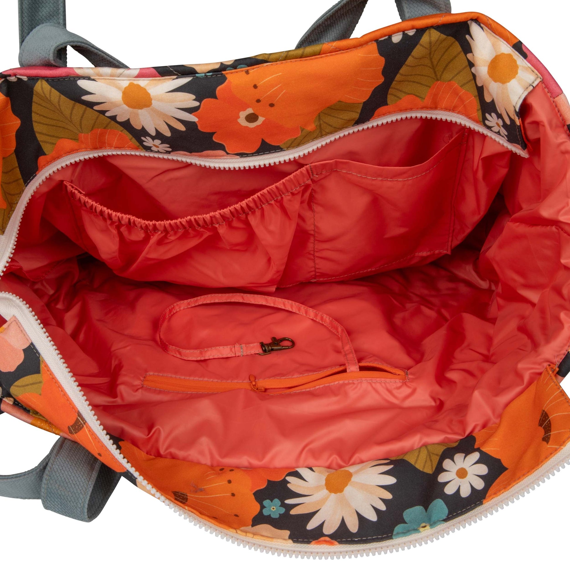 softly lit floral weekender bag on a cozy blanket, open to show its spacious waterproof interior