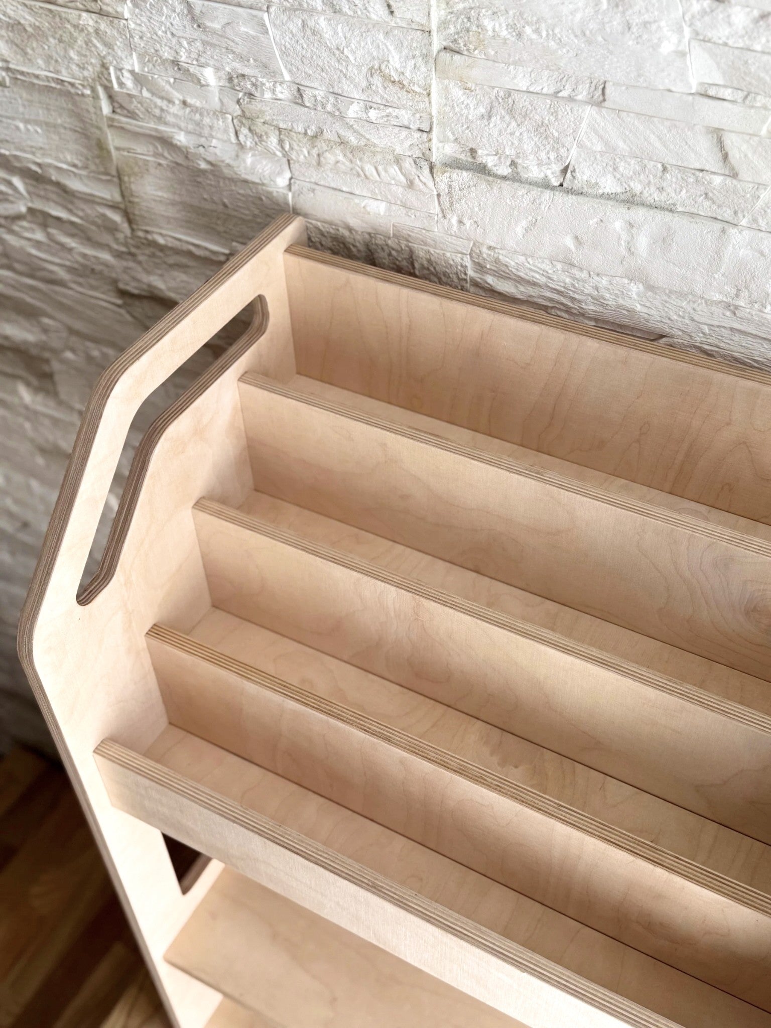 a playful low-angle shot of the birch bookshelf, filled with colorful books and a teddy bear peeking out