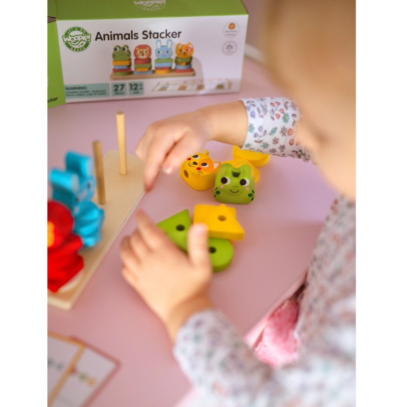 a child's small hands carefully placing a wooden giraffe block onto the montessori puzzle pyramid
