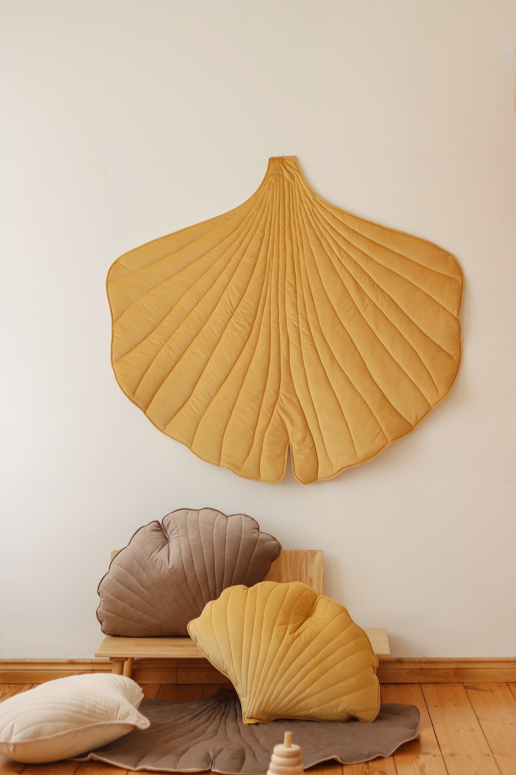 bold yellow ginkgo leaf playmat on a dark floor, showcasing its vibrant color and artisan-crafted texture