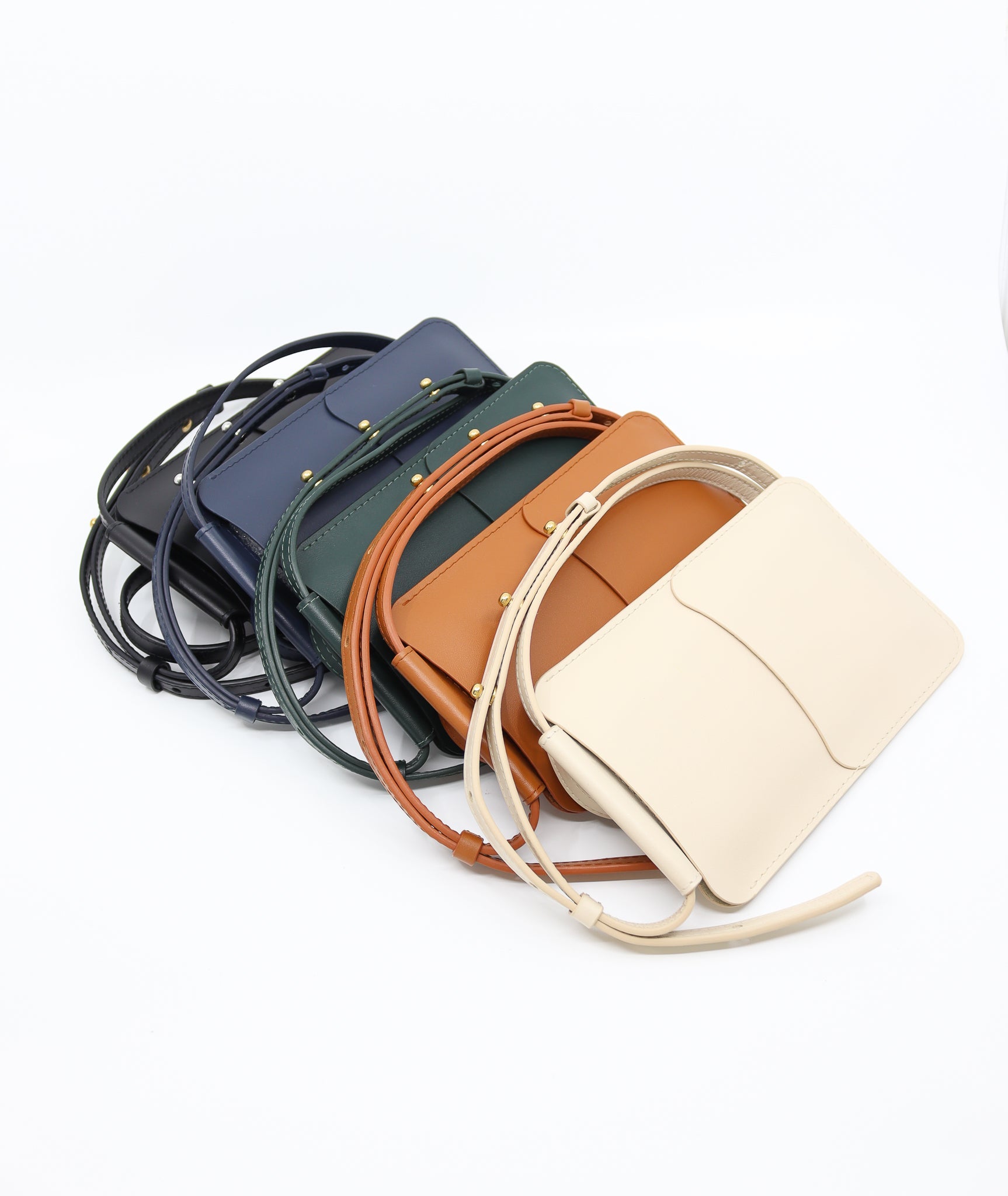 navy leather phone bag with three adjustable strap buttons and card slots shown in natural light