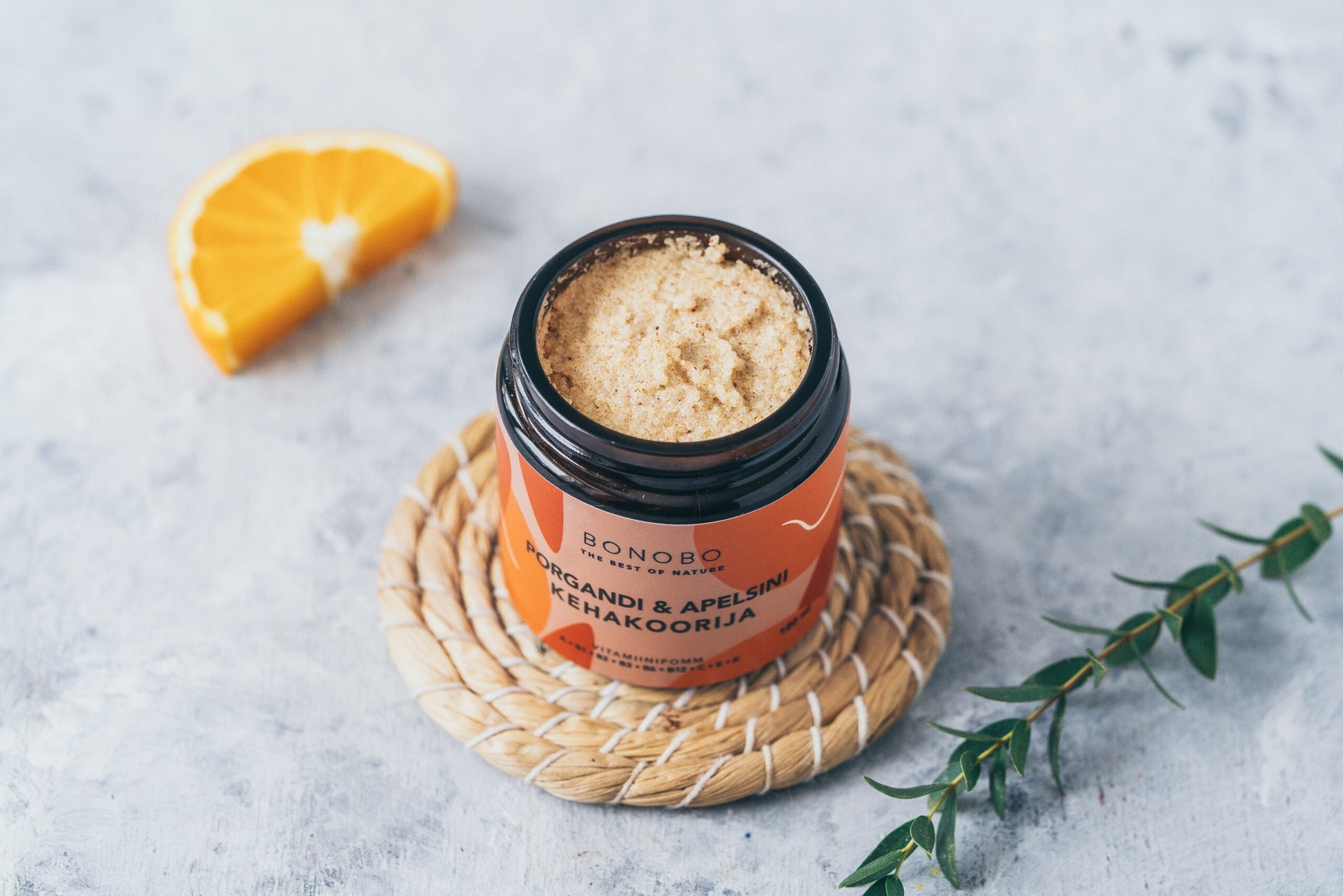 a contemporary leather gift box open to reveal four vibrant body scrubs in warm, inviting light