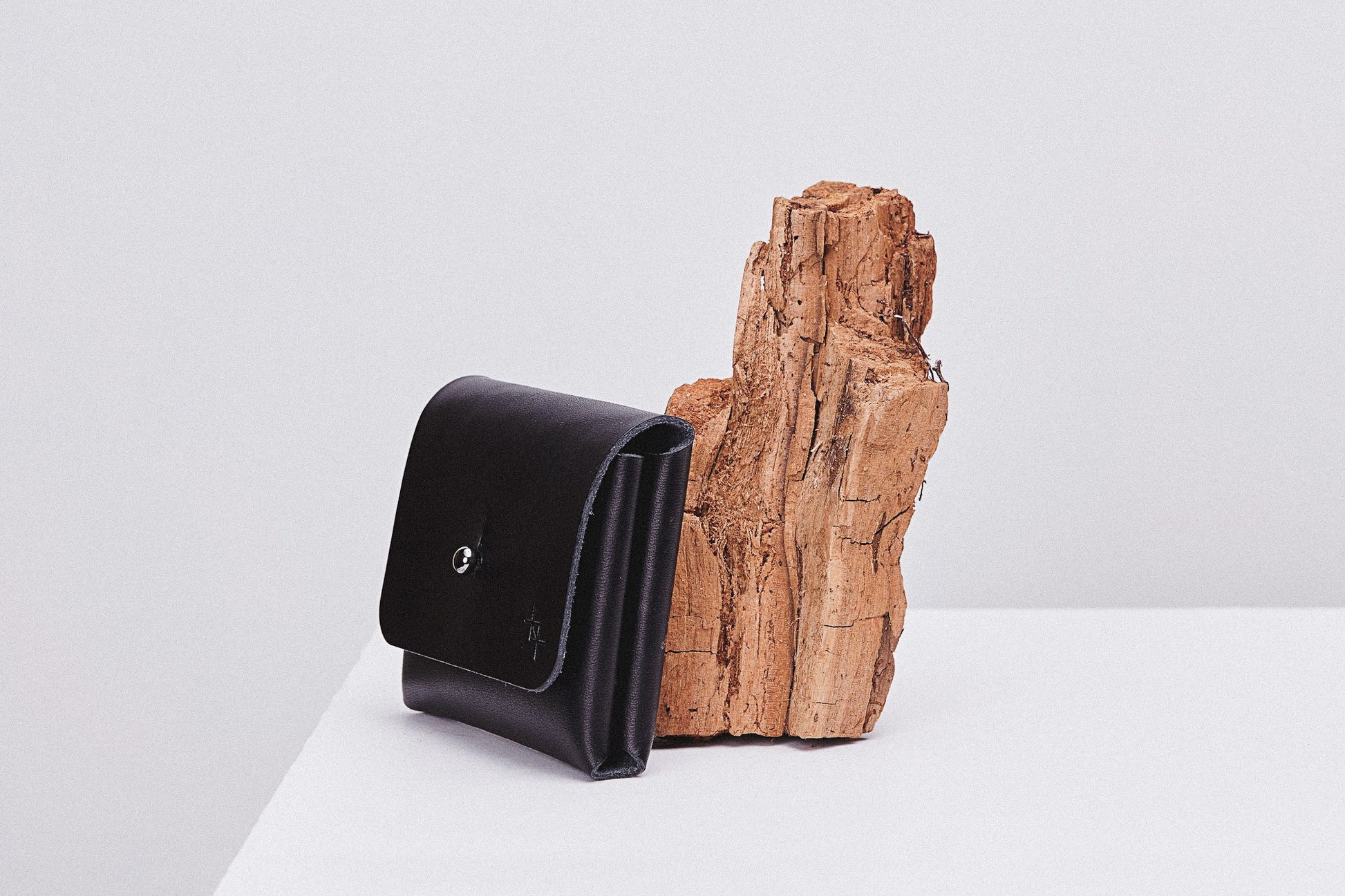 softly lit minimalist leather pouchie wallet with its adjustable strap resting on a cozy surface