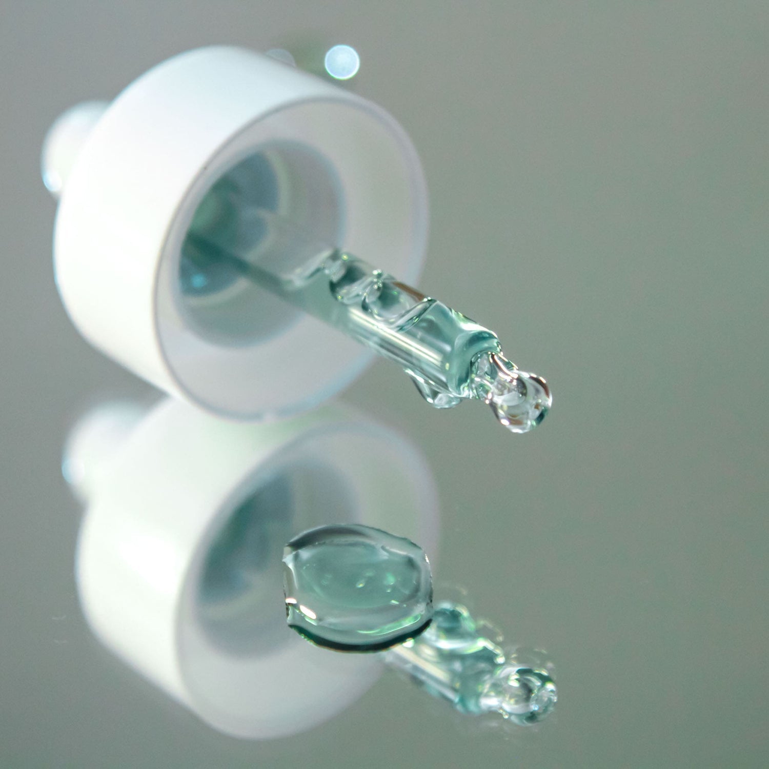 practical close-up of recalm face oil serum dropper dispensing golden oil onto skin