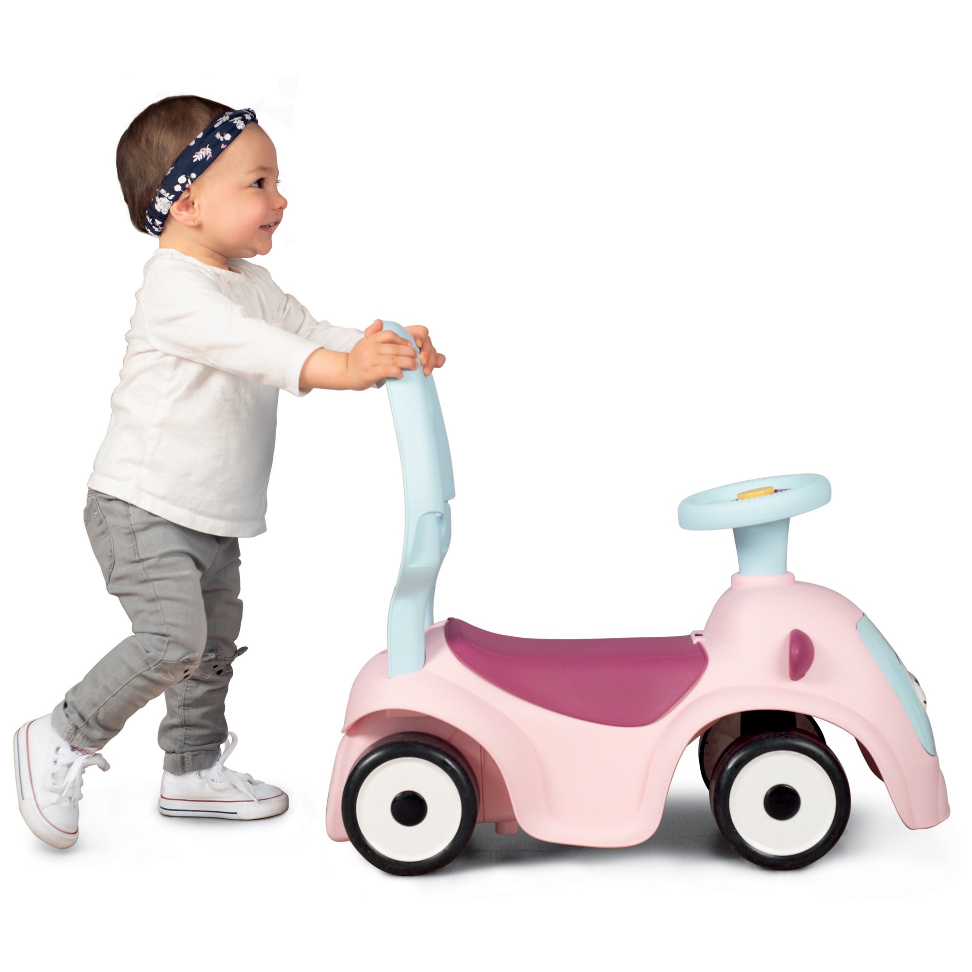 a child playing with the pink maestro 3in1 ride-on, showcasing its interactive eyes and storage compartment in a sunlit garden
