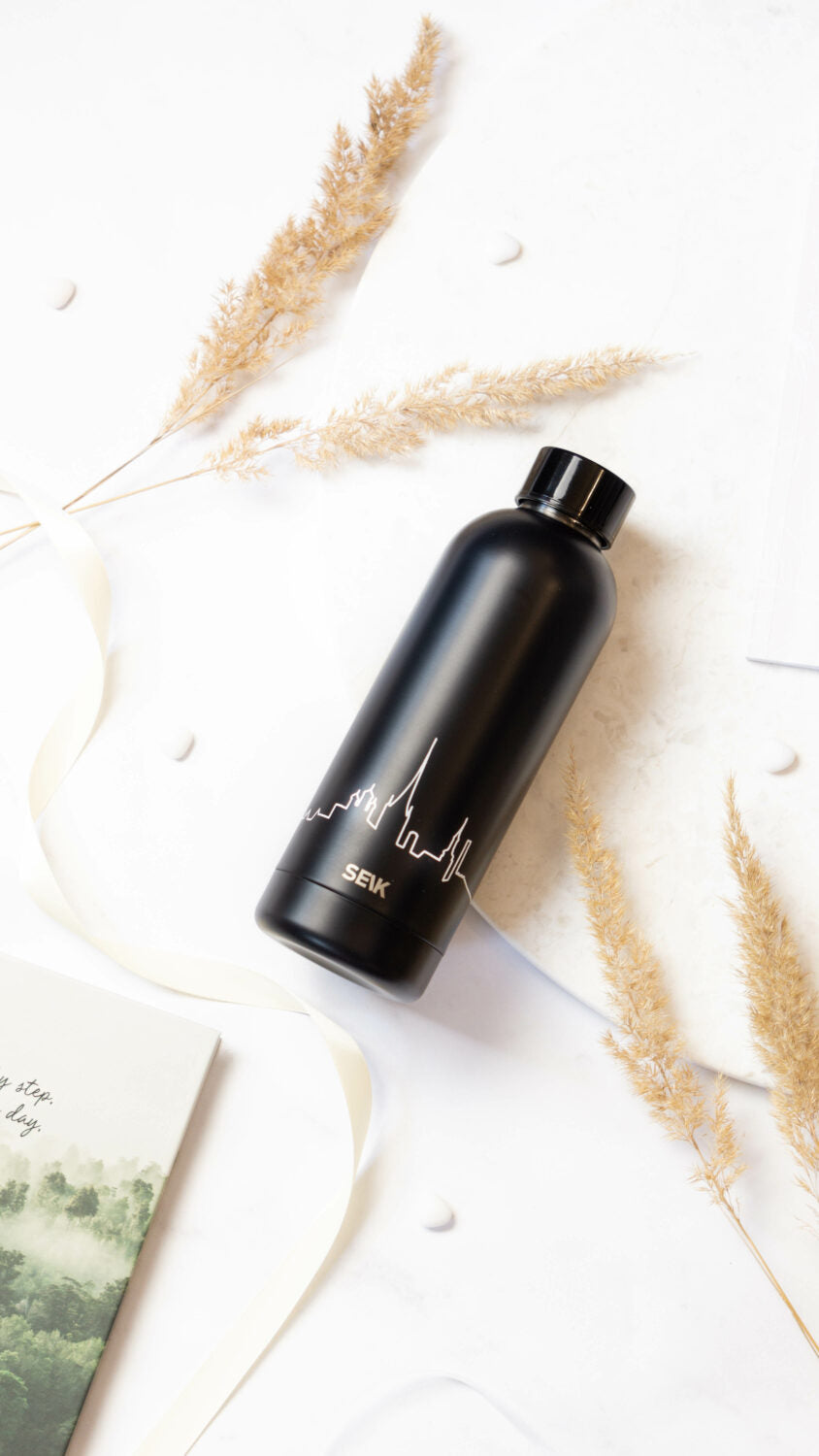 tallinn skyline water bottle held in hand against a coastal backdrop