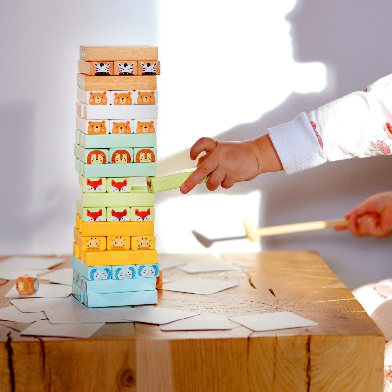 child's hands carefully placing a pastel wooden block on the shaky tower game