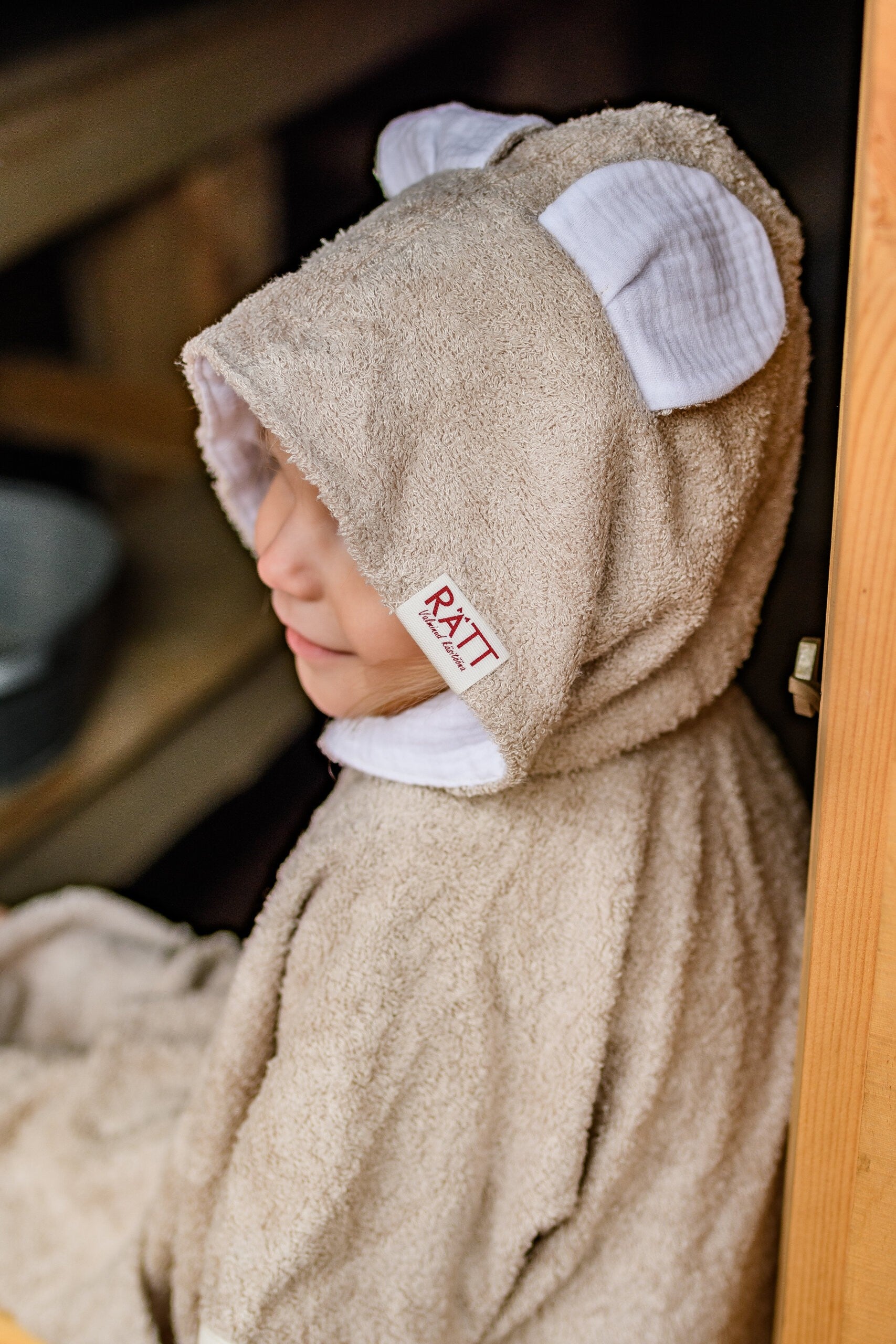 elegant toddler in a soft bamboo poncho, showcasing the refined side-seam tailoring and hood detail