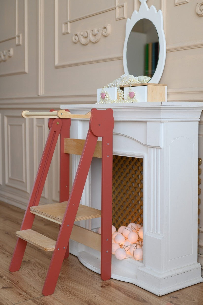 foldable baltic birch step stool for kids folded flat against a wall in a sunlit kitchen