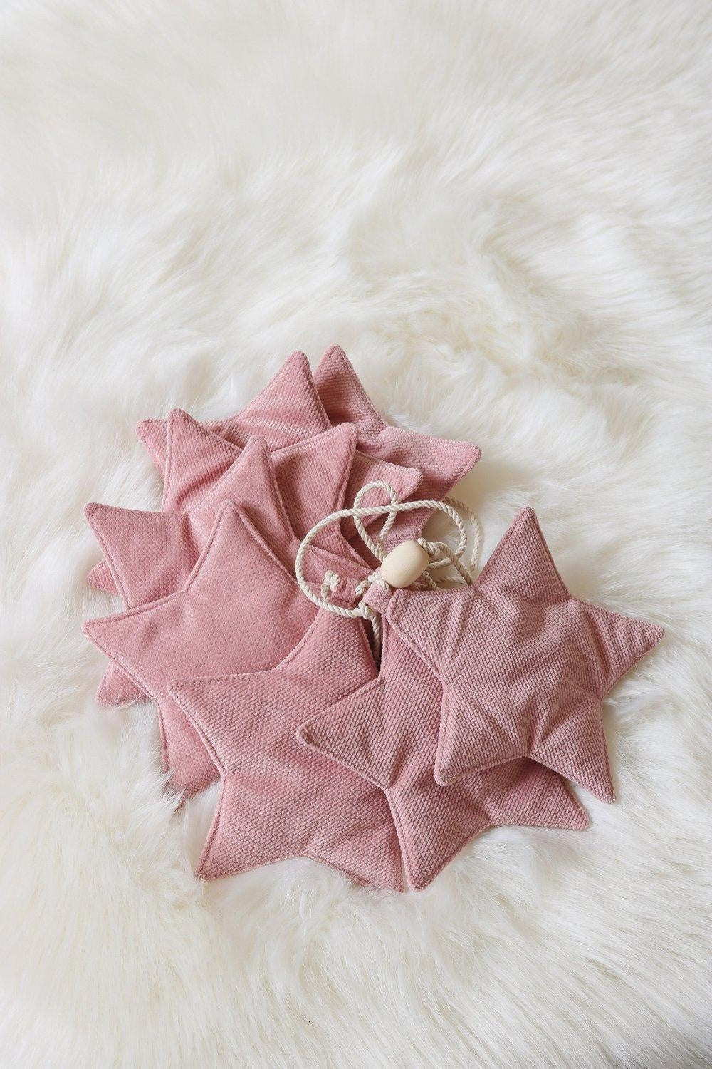soft pink velvet star garland draped gently over a crib with warm morning light