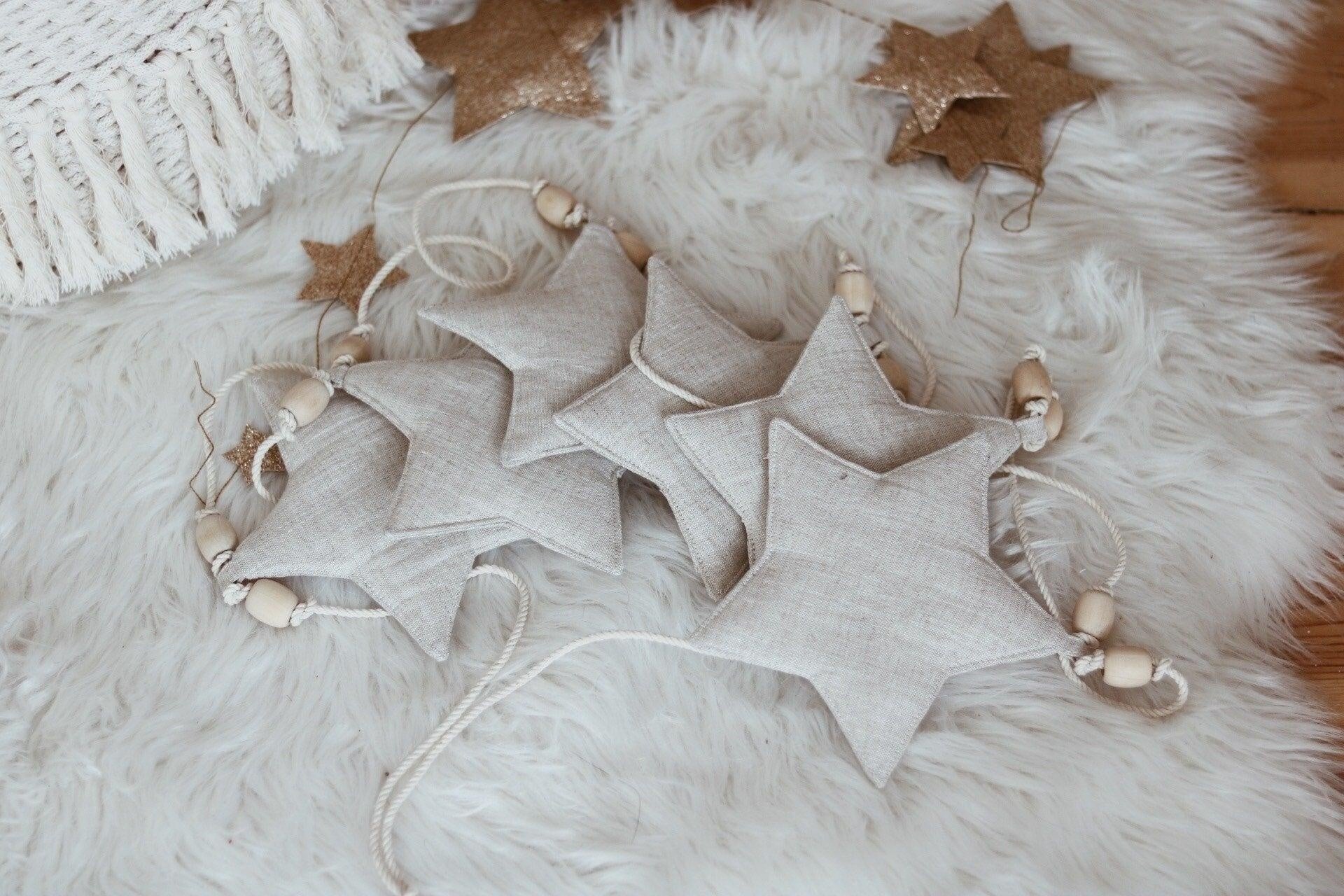 close-up of a sand-dusted linen star from an artisanal nursery garland, showcasing its textured surface and wooden bead detail