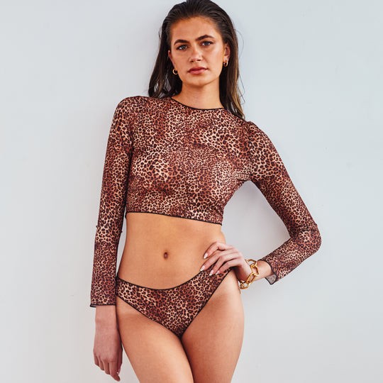 confident woman in tan-through long sleeve bikini set - mini feline, sunlit beach backdrop, bold and stylish