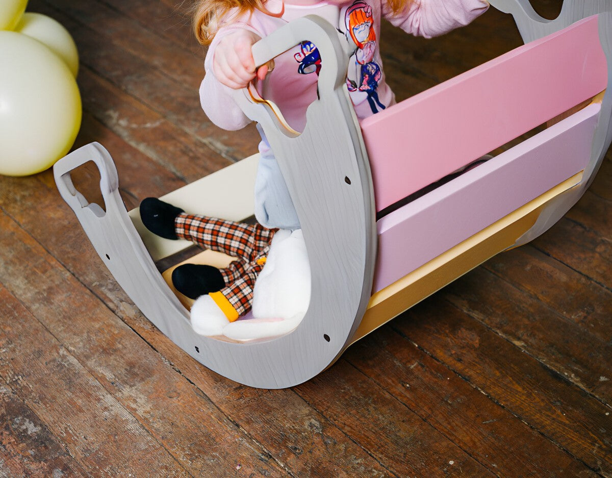 a child's hand gently touching the smooth birch plywood curve of the rainbow climber and swing