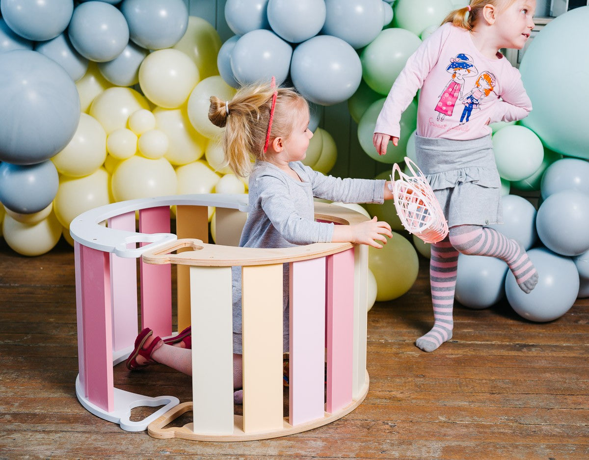 side view of a toddler using the birch plywood rainbow climber as a shop counter for imaginative play