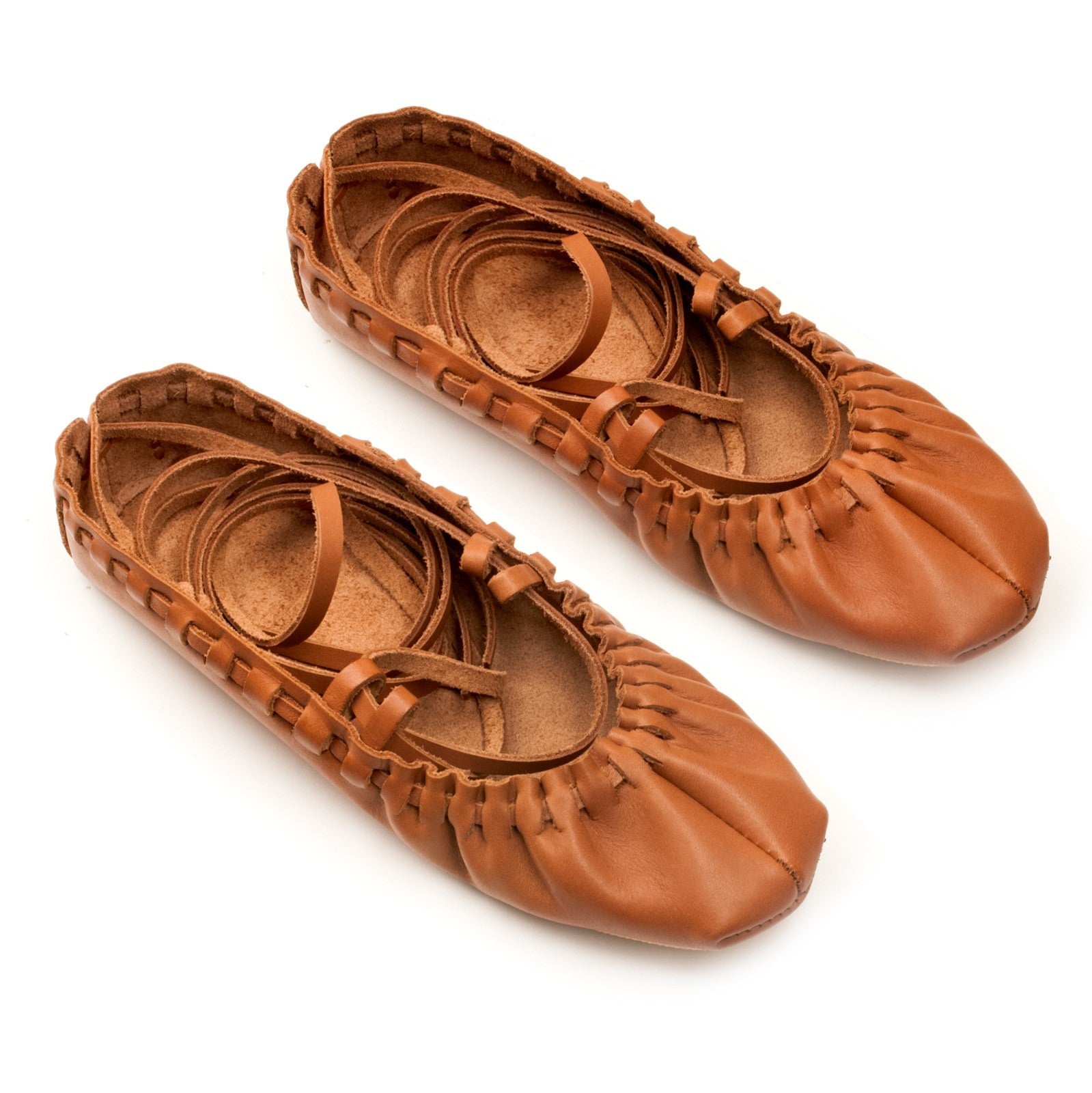 playful close-up of artisan leather dancing shoes with laces untied on a sunlit studio floor