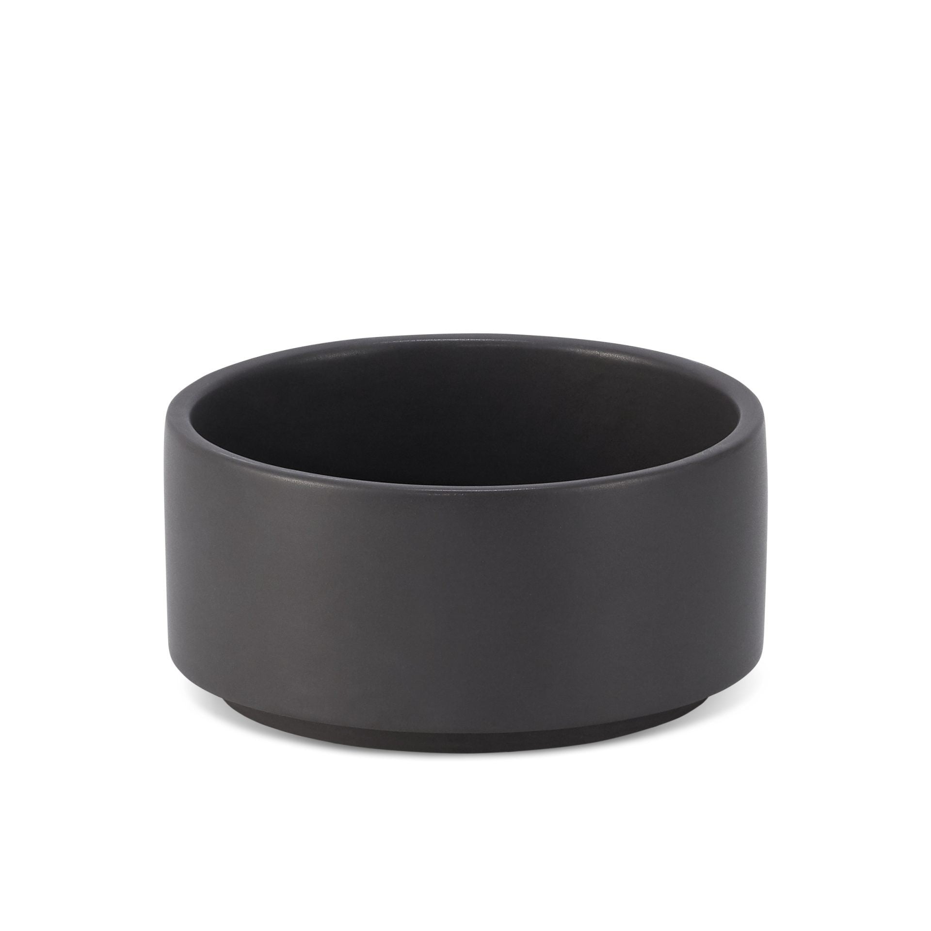 bold black vuku ceramic pet bowl on a dark slate surface, showcasing its sleek and stable design