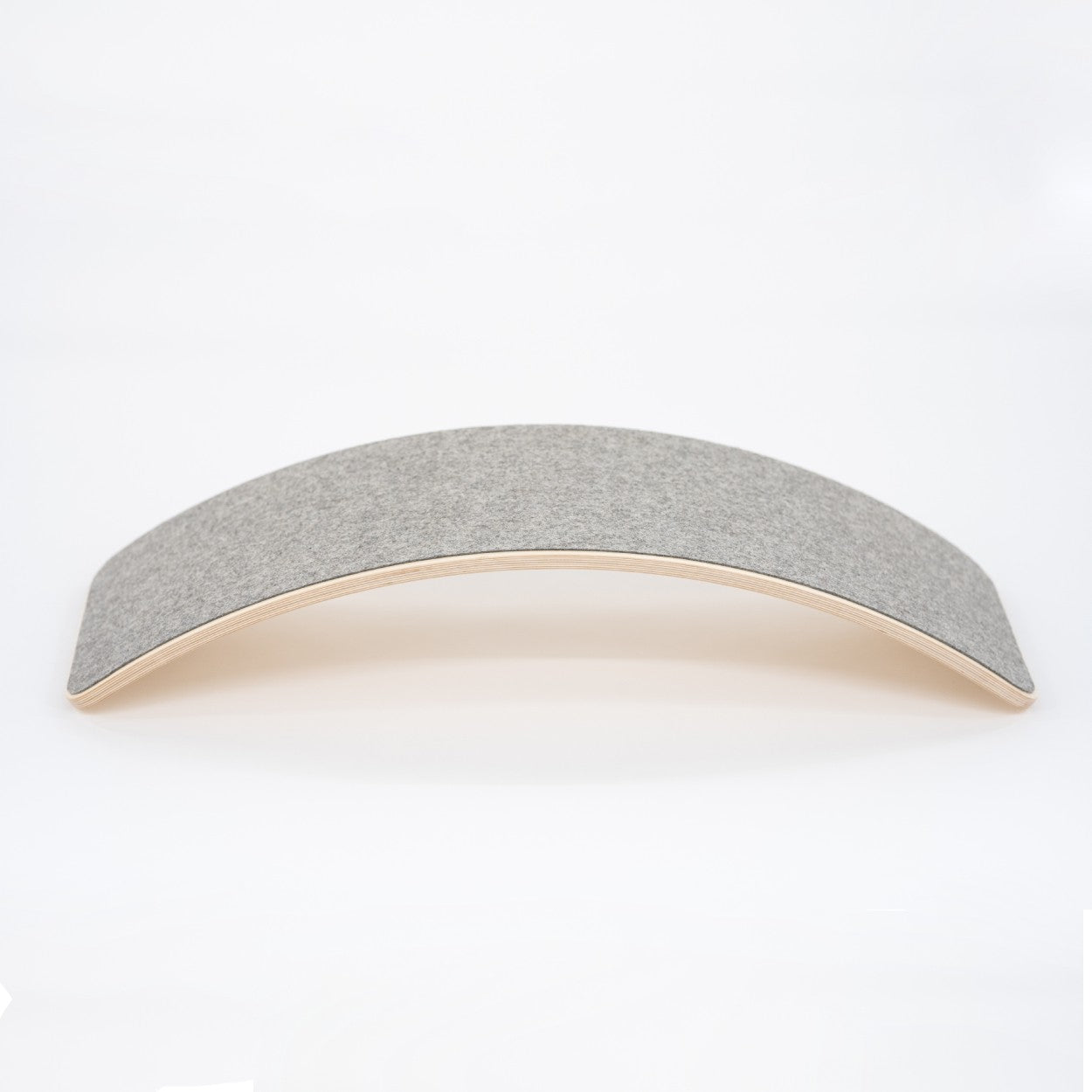 a child gently rocking on a wooden balance board with soft grey felt in a cozy, sunlit room