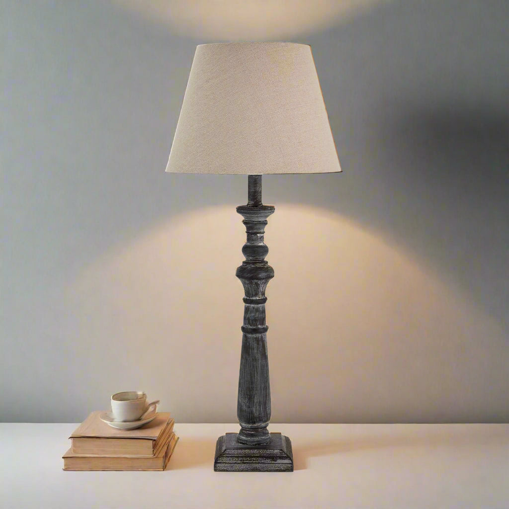 bold wooden column lamp casting a dramatic pool of light on a dark surface