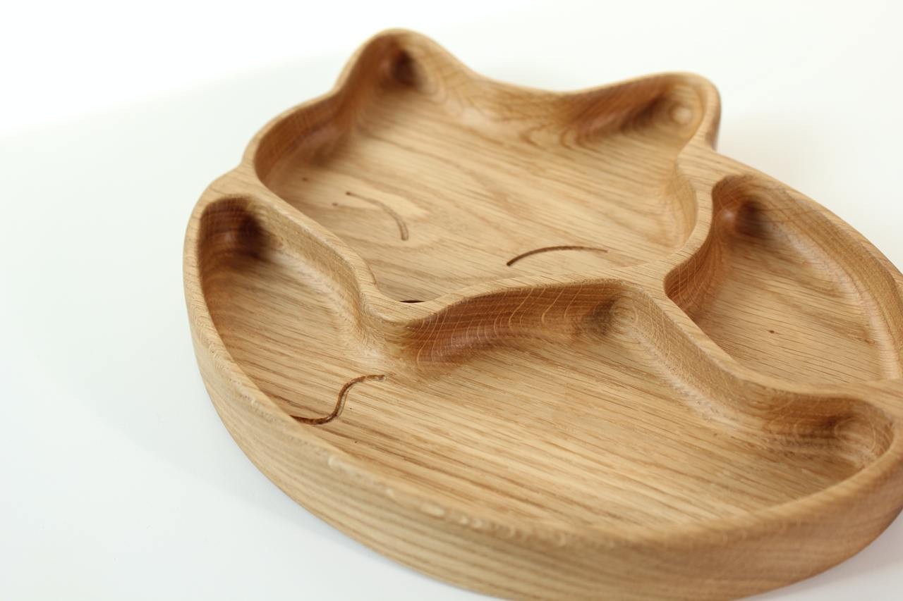soft-lit close-up of a handcrafted wooden kids plate with a gentle fox design and three food sections