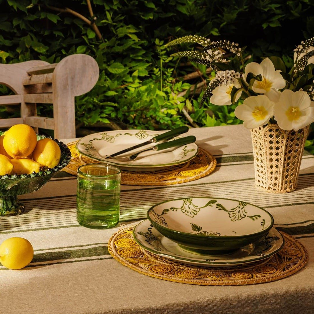 Hand-painted Casa by Josephine Jenno tableware, a scalloped pink-edged plate, pink glass tumblers and dahlias on a rattan table setting